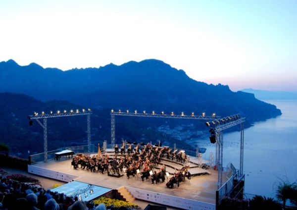 Outdoor orchestra performance at sunset by the sea.