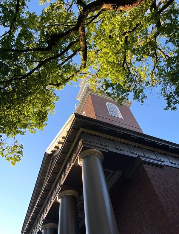 Low angle view of a brick building with columns against a blue sky.