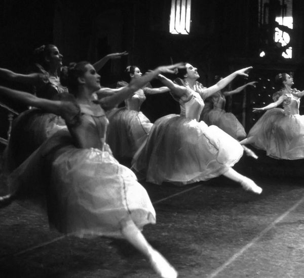 Ballet dancers performing a leap on stage.