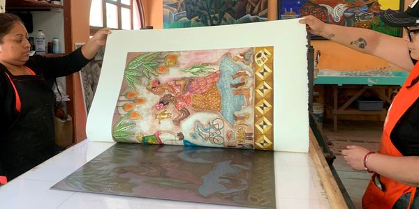 Dos mujeres muestran una hoja con una obra de arte.