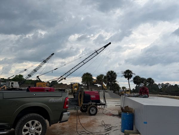 Construction site with cranes, a truck, and a worker under a cloudy sky.