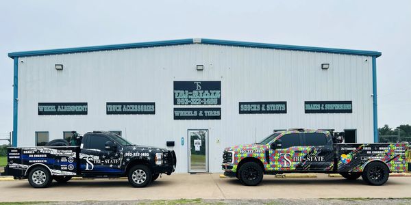 2 of our 24/7 Roadside trucks in front of four building
