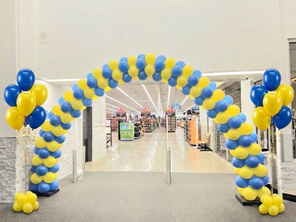 Arco de globos amarillos y azules en la entrada de una tienda.
