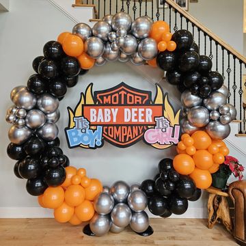 A Harley-Davidson themed baby gender reveal balloon wreath with orange, black, and silver balloons.