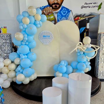 Blue and white balloon decoration setup with a seashell-themed sign.
