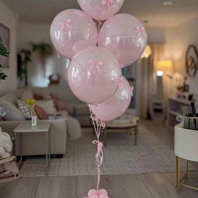 Elegant pink balloons with bows arranged in a cozy living room.