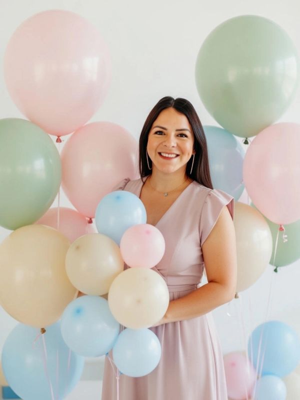 Mujer sonriente con globos de colores pastel.