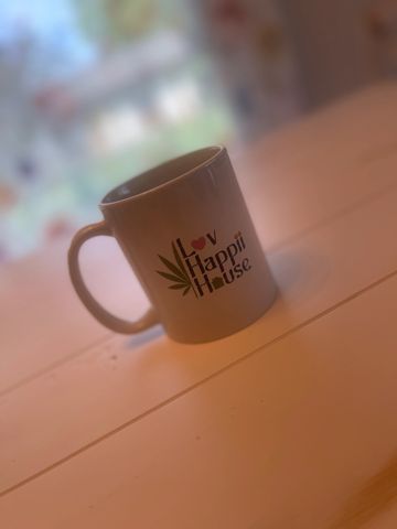 White mug with "Lov Happii House" text on a wooden surface.
