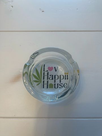 Clear glass ashtray with "Lov Happii House" text and cannabis leaf design.
