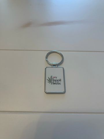 Metal keychain with 'Lov Happii House' text and leaf design.