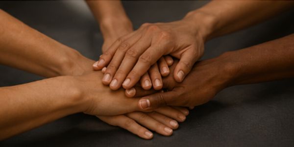 A group of diverse hands stacked together as a symbol of unity.
