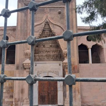 Kafesli pencere önünde tarihi taş yapı ve kapı.