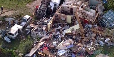 Aerial view of building collapse and wrecked vehicles.