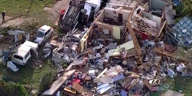 Aerial view of building collapse and wrecked vehicles.