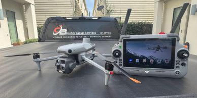 Drone and remote controller with screen displayed on a car hood.
