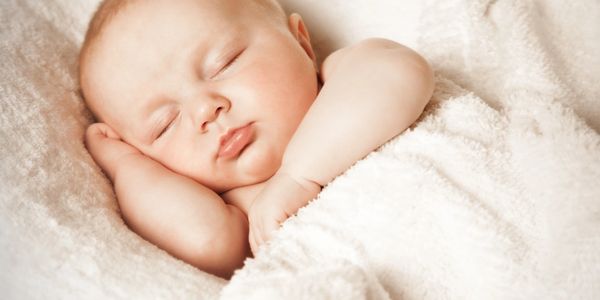A peaceful baby sleeping wrapped in a soft white blanket.