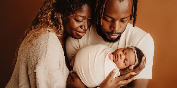 Parents lovingly cradle their newborn baby wrapped in a blanket.