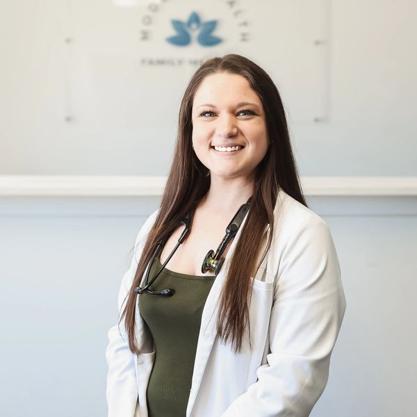 Smiling female doctor with long hair and stethoscope in a white coat.