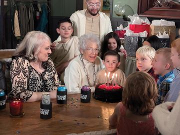 A family celebrates grandma's birthday with a cake and candles in the formal banquet space of the Ovid Inn Event Center