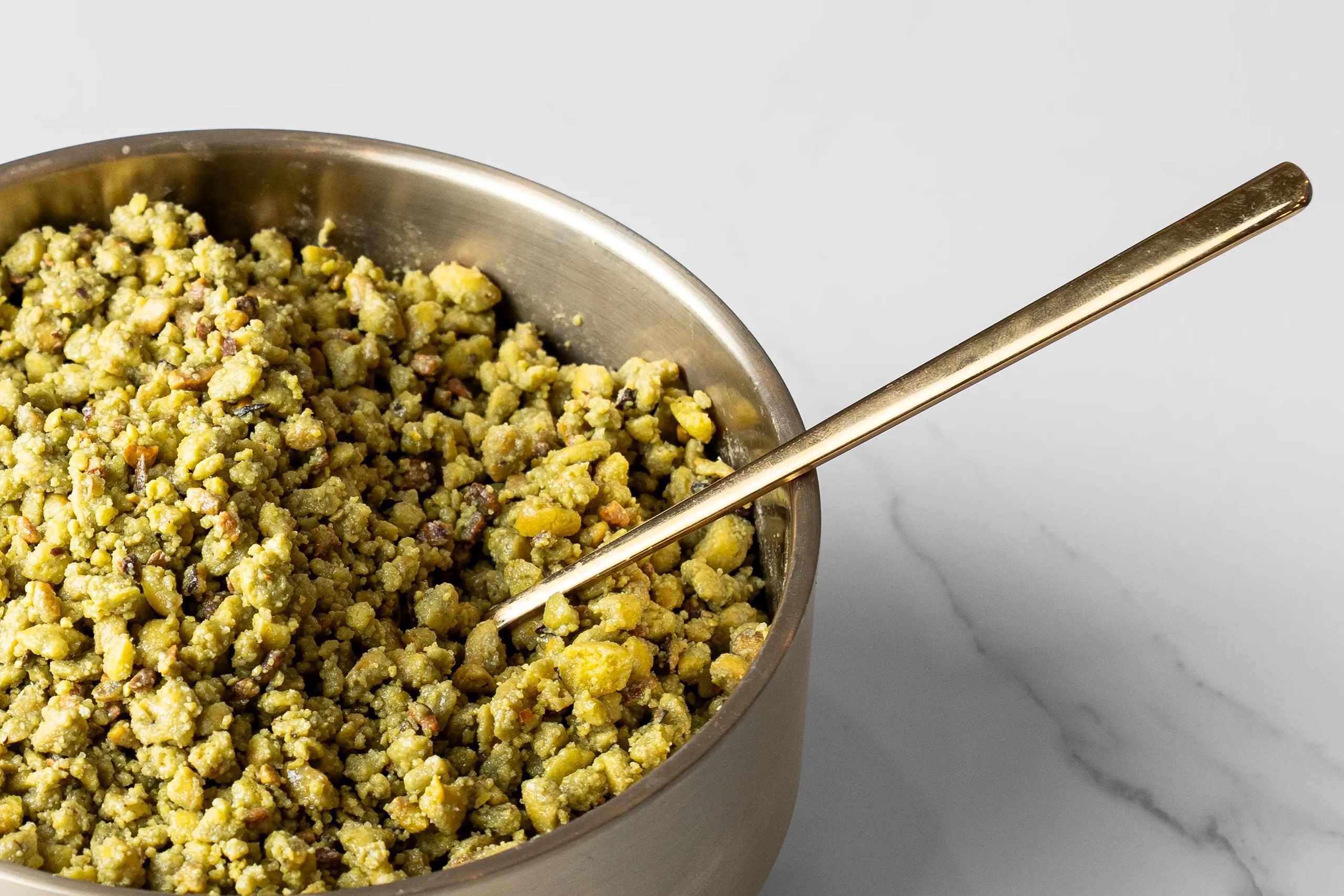Bowl of crumbled food with a spoon.