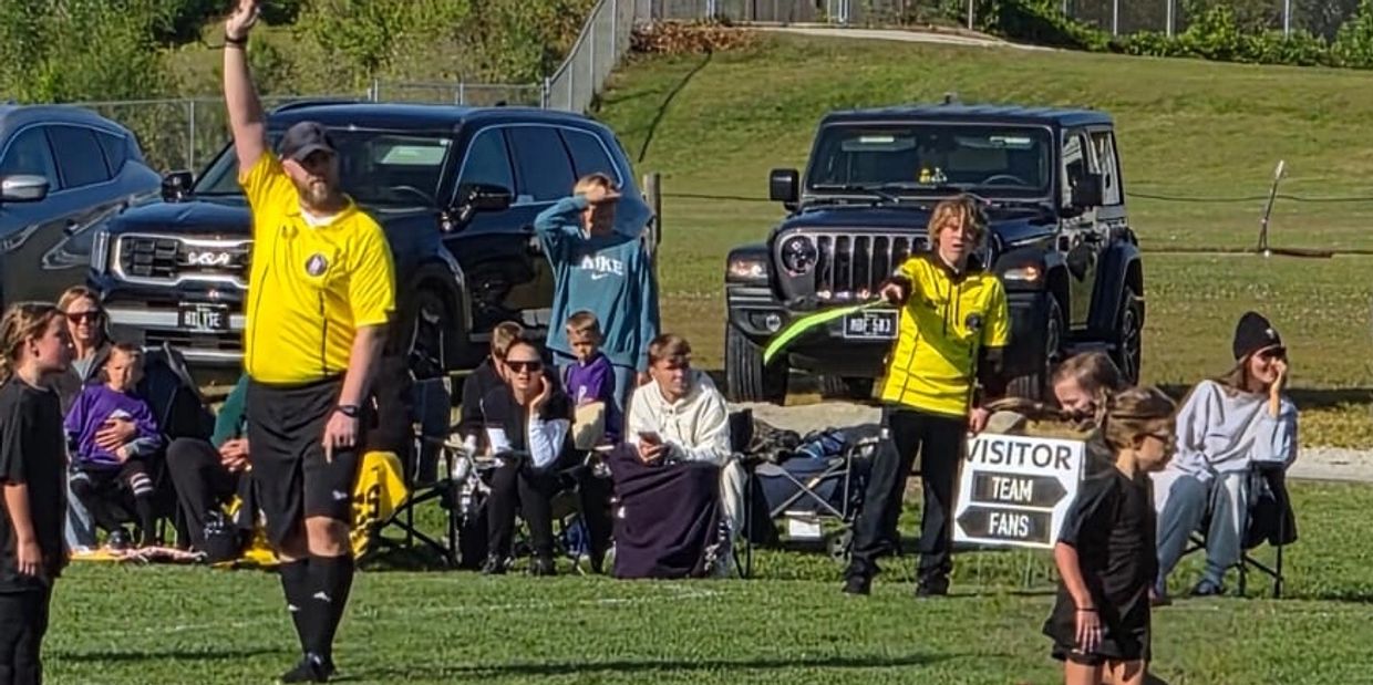 Referee and assistant signaling during youth soccer game.