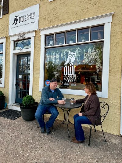 Two people enjoying coffee outside Owl Canyon Coffee.