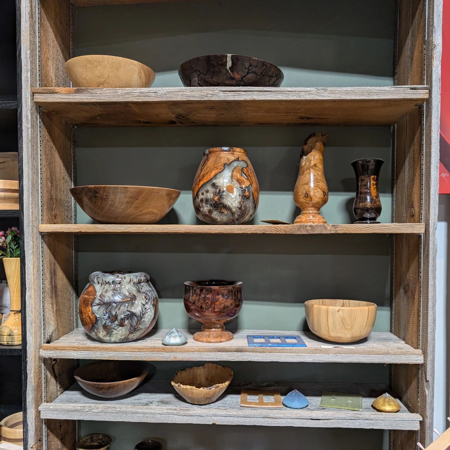 Wooden bowls and vases displayed on rustic wooden shelves.