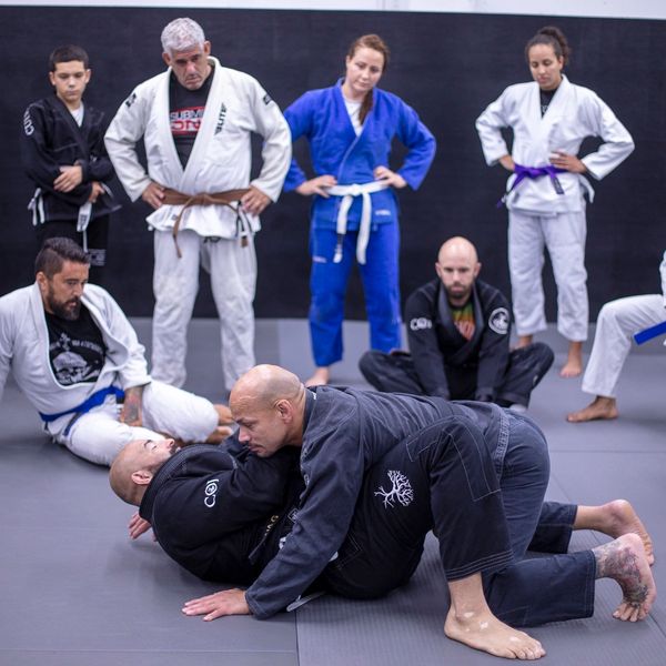 People practicing Brazilian Jiu-Jitsu on mats.