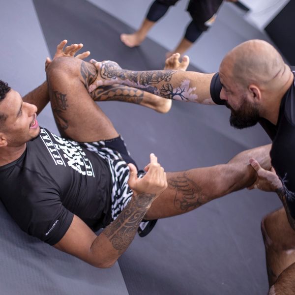 Two men practicing Brazilian Jiu-Jitsu on a mat.