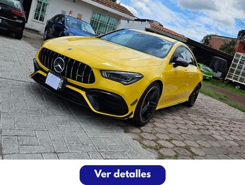 Yellow Mercedes-Benz AMG parked on a driveway under blue sky.