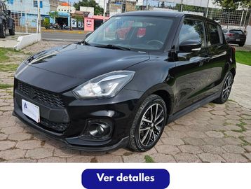 Auto compacto negro estacionado en pavimento.