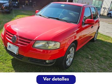 Red Volkswagen hatchback parked on grass in daylight.