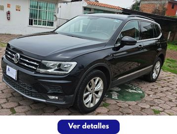 Volkswagen SUV parked on a cobblestone driveway near a house.