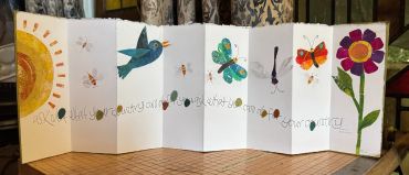 Accordion-style illustrated nature book with sun, birds, butterflies, and flower.