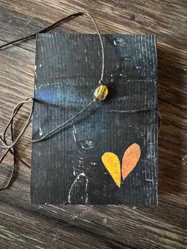 Black handmade notebook with a heart and string closure.