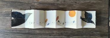 Accordion-style artwork with birds and an orange sun motif.