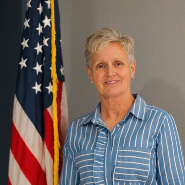 Woman standing next to an American flag, smiling.