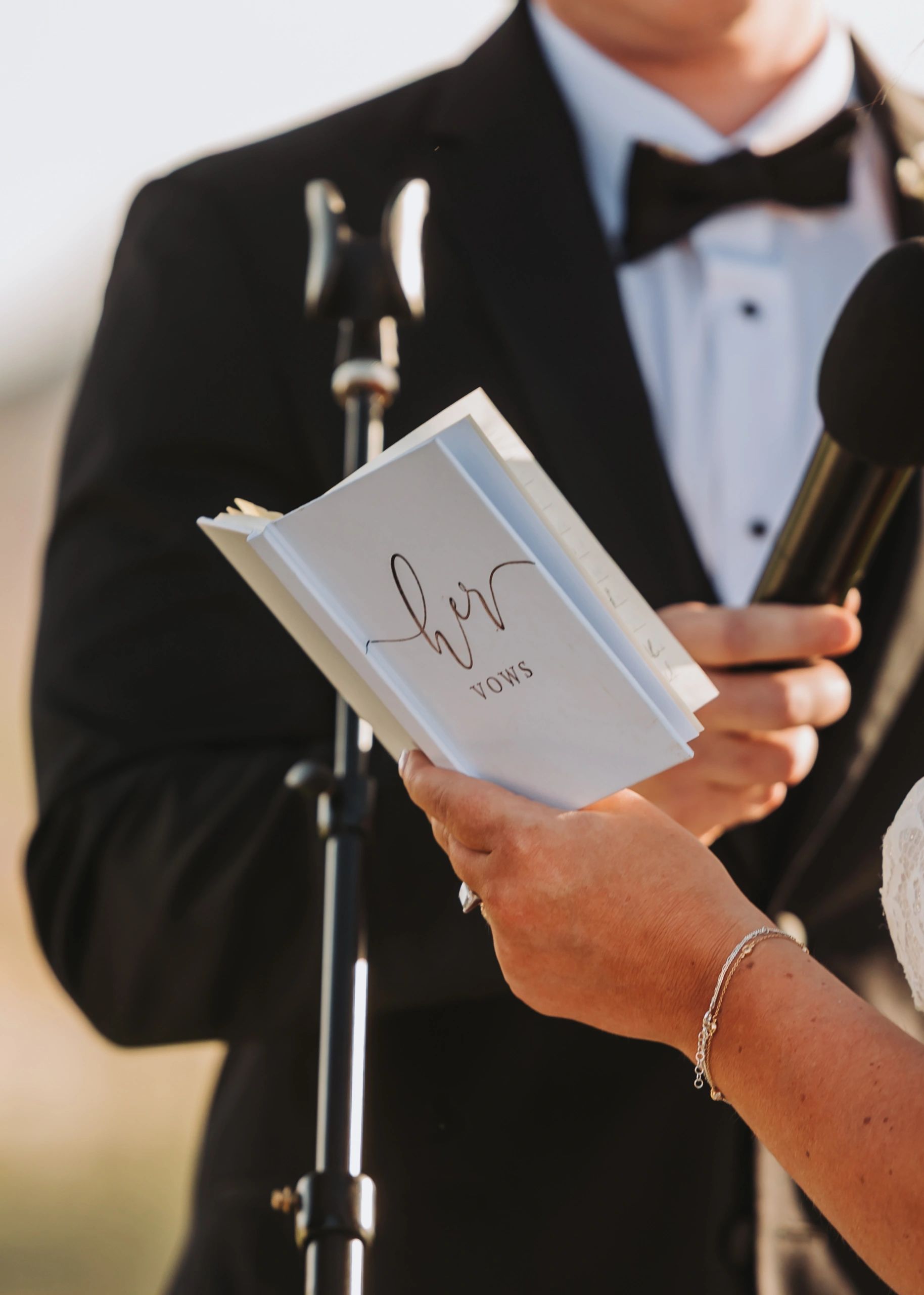 Bride holding vow book during wedding ceremony.
