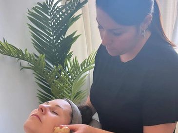 A woman receives a facial treatment from a beautician indoors.