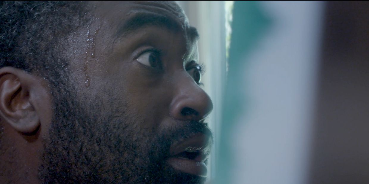 Close-up of a sweating man looking anxiously to the side.