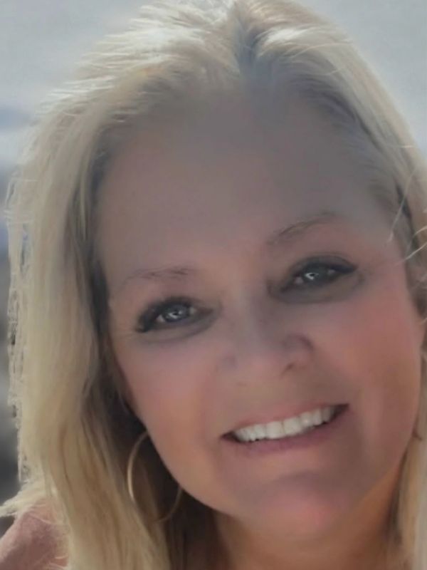 Close-up of a smiling woman with blonde hair.