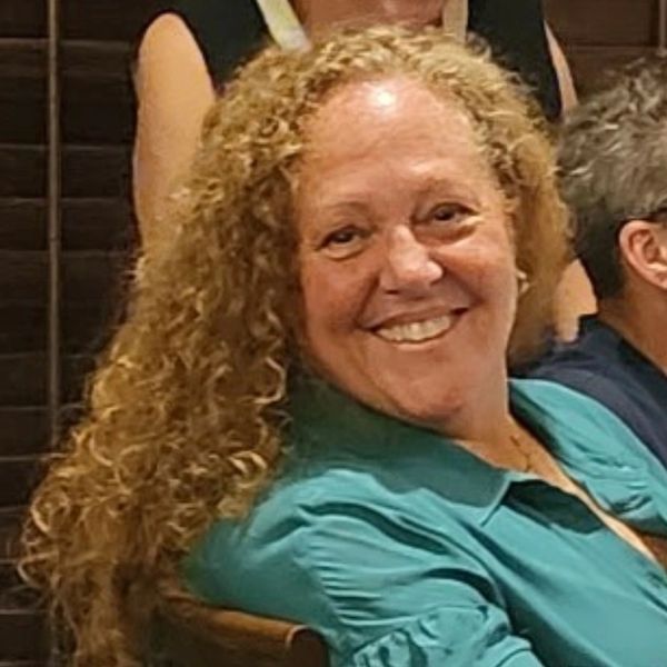 Smiling woman with curly hair in a teal shirt.