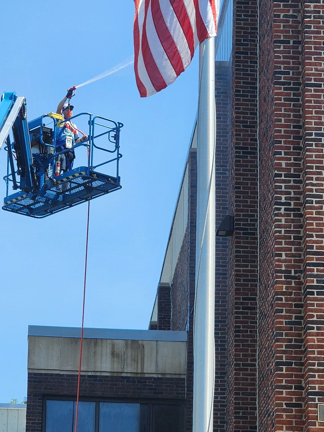 Brick cleaning on commercial building in patriotic setting.