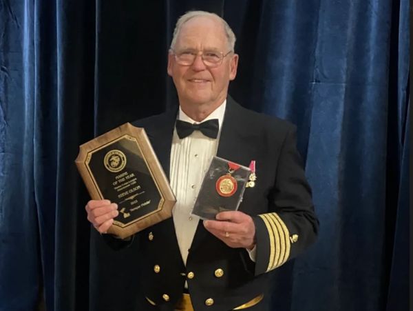 Steve in formal military attire holding an award plaque and medal.