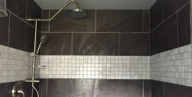 Custom shower stall. Featuring large format tile. Accent band and shower caddy with hand wand.