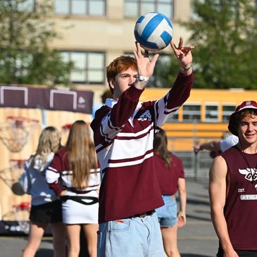 Young man playing a ball toss game at an outdoor event.