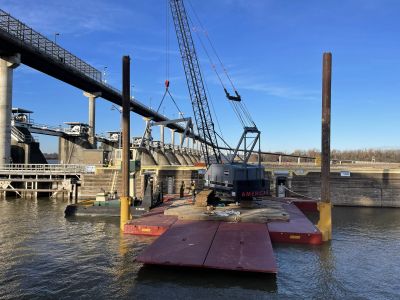 Crane on a barge near a dam on a sunny day.