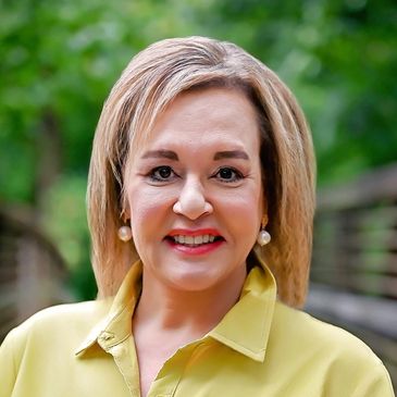 Smiling woman in yellow blouse outdoors.