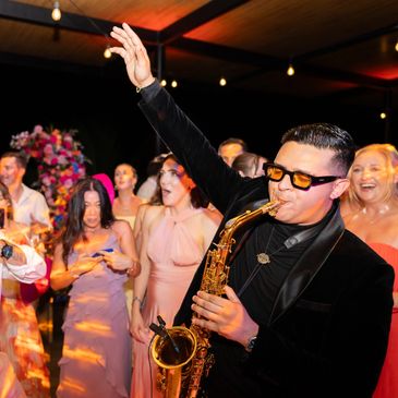 Crowd dancing and man playing saxophone on the dancefloor.