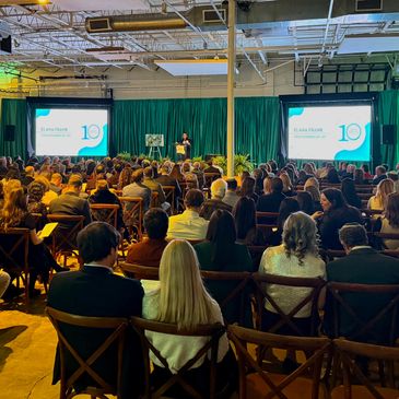 Audience attending a presentation in a large hall with dual screens.